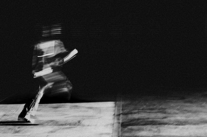 A runner leaping over the camera against open sky.